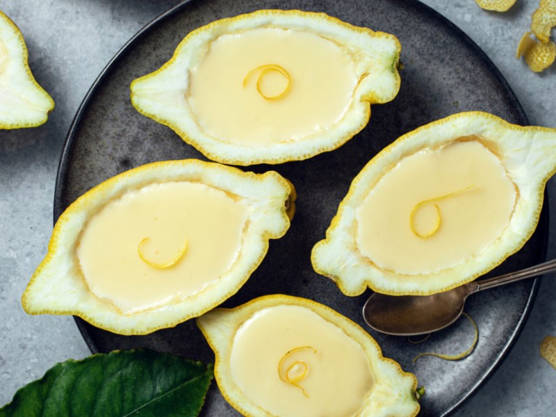 Dessert in Zitronenhälften auf schwarzem Teller.