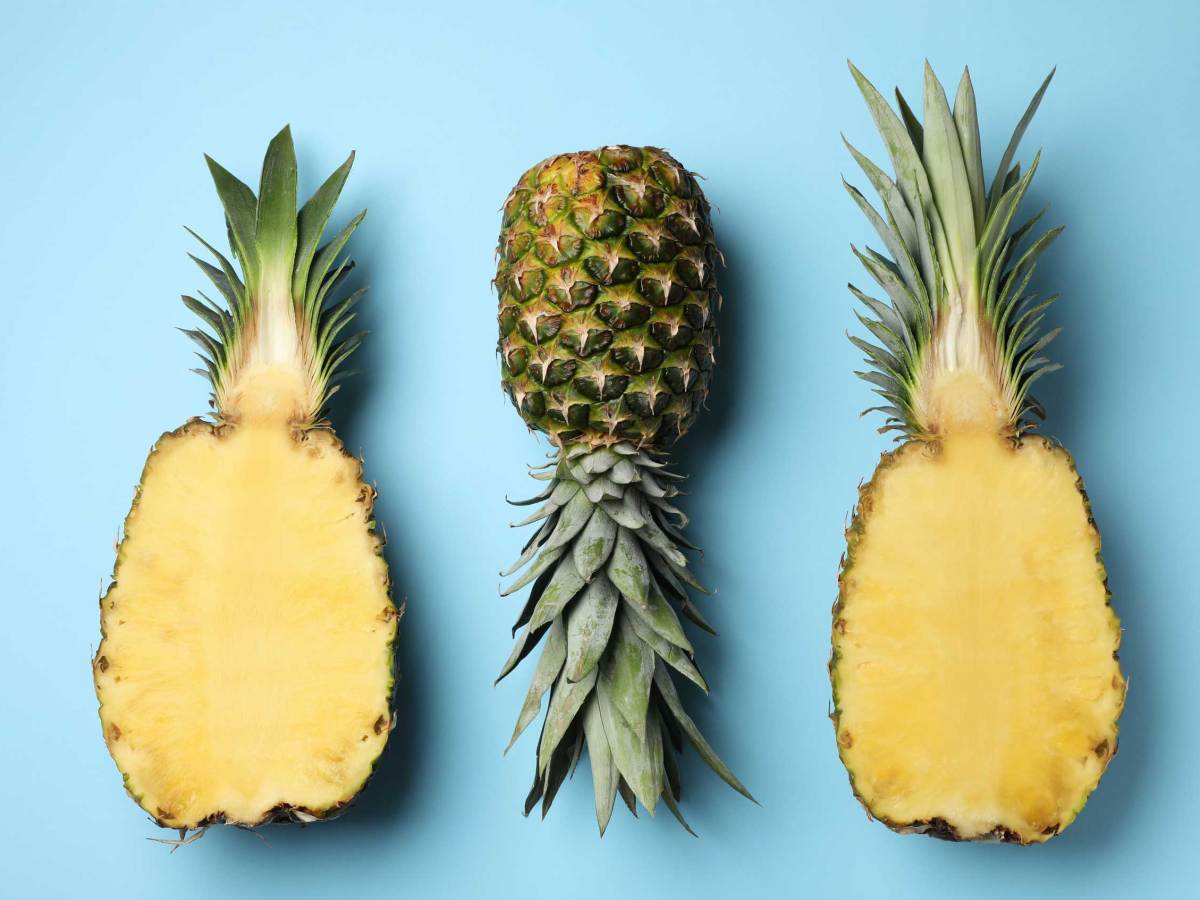 Frische ganze und geschnittene Ananas auf hellblauem Hintergrund, Ansicht von oben