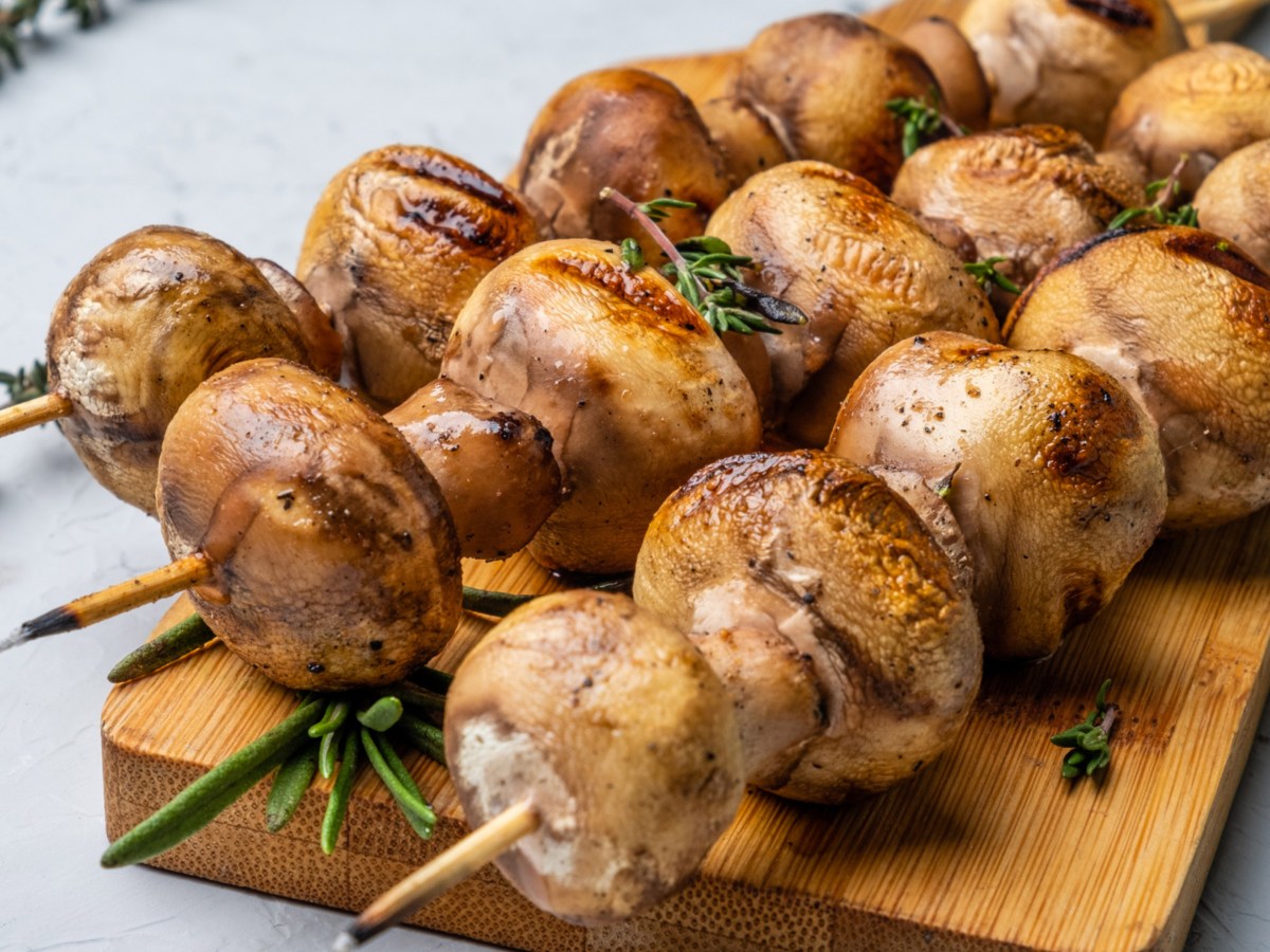 Gegrillte Champignons Spie&szlig;e auf einem Holzbrett.