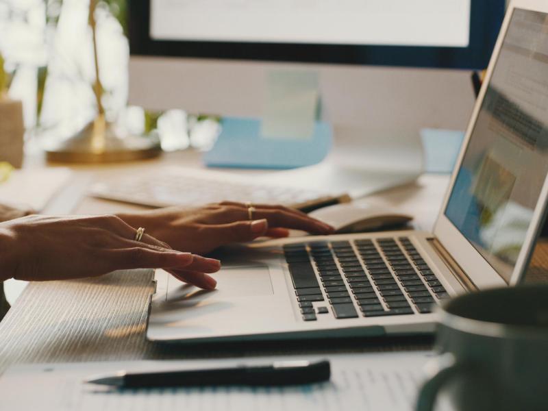 Frau tippt auf einem Laptop.