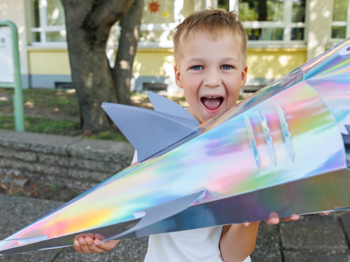 Junge an seinem ersten Schultag mit einer Schult&uuml;te in Hai-Form.