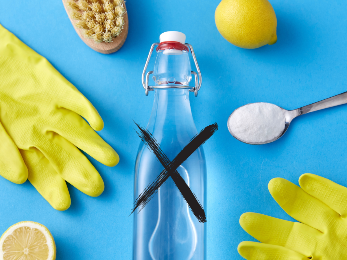 Handschuhe, Zitrone, eine Flasche Essig und Natron auf einem Löffel liegen vor einem blauen Hintergrund