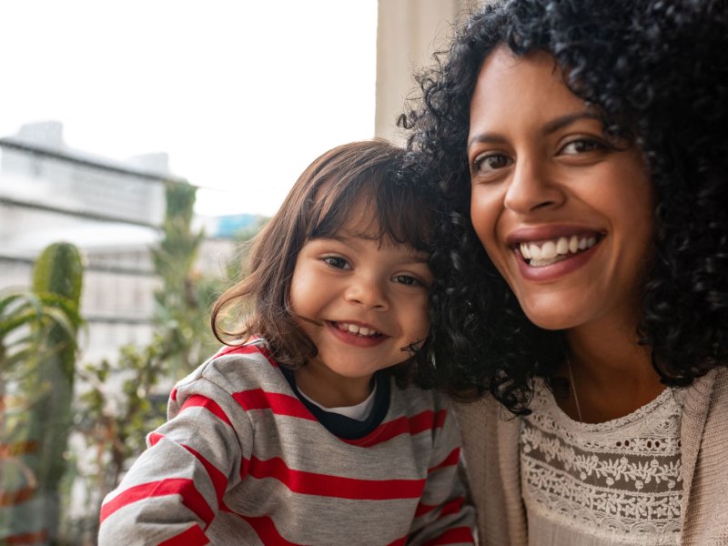 Lachende Mutter mit ihrer Tochter auf dem Balkon ihres Zuhauses.