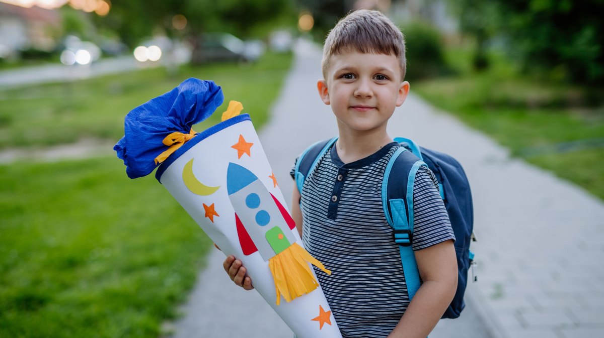 Junge mit Schultüte auf dem Weg zu seinem ersten Schultag.