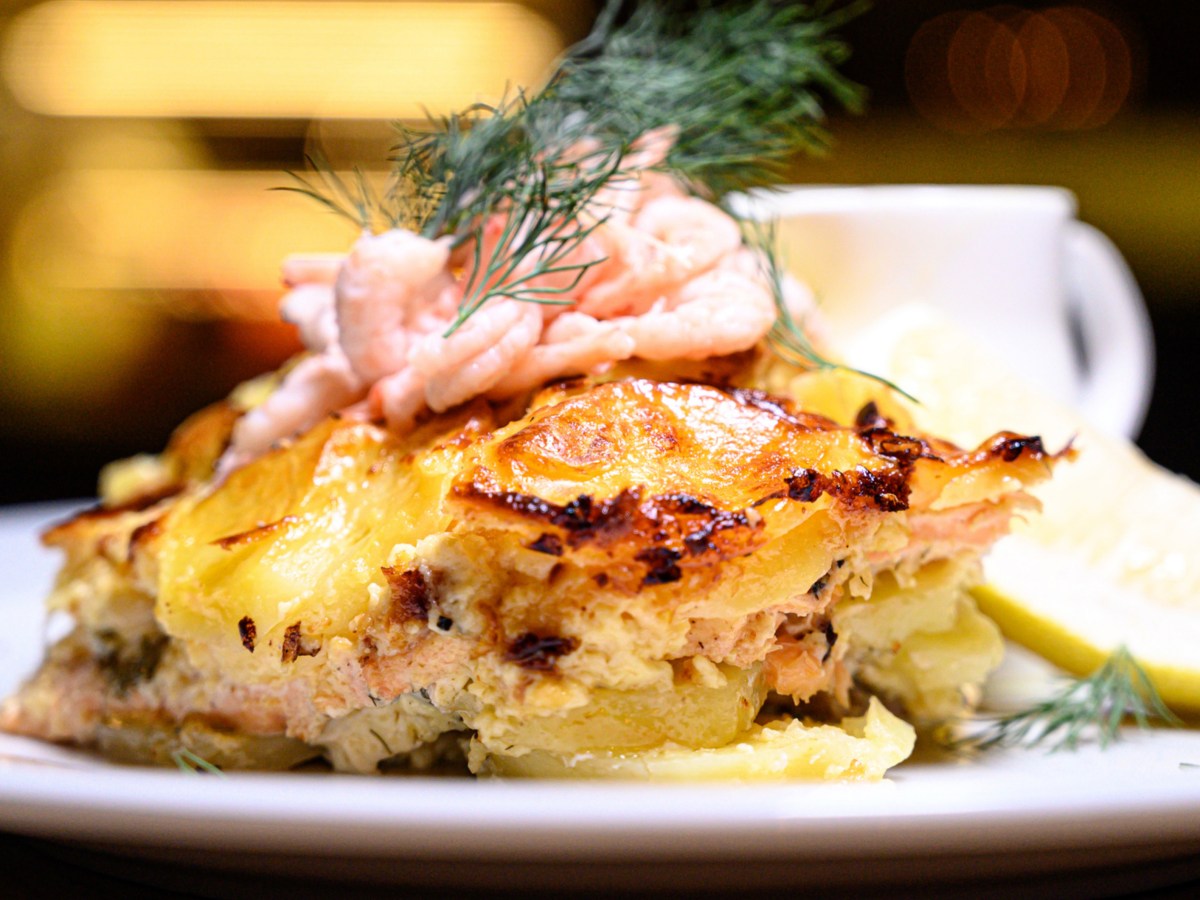 Kartoffelauflauf mit Lachs und Dill auf einem wei&szlig;en Teller.
