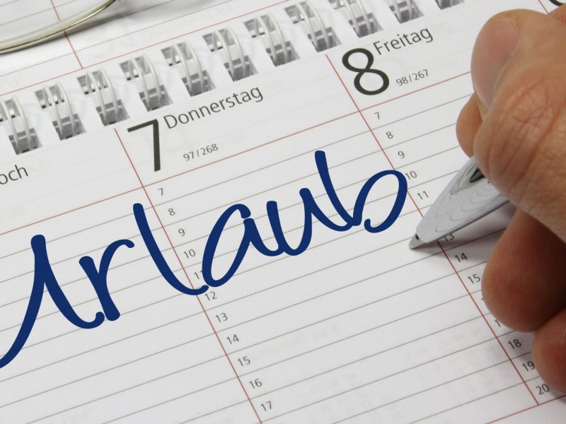 Person schreib „Urlaub“ in seinen Terminkalender