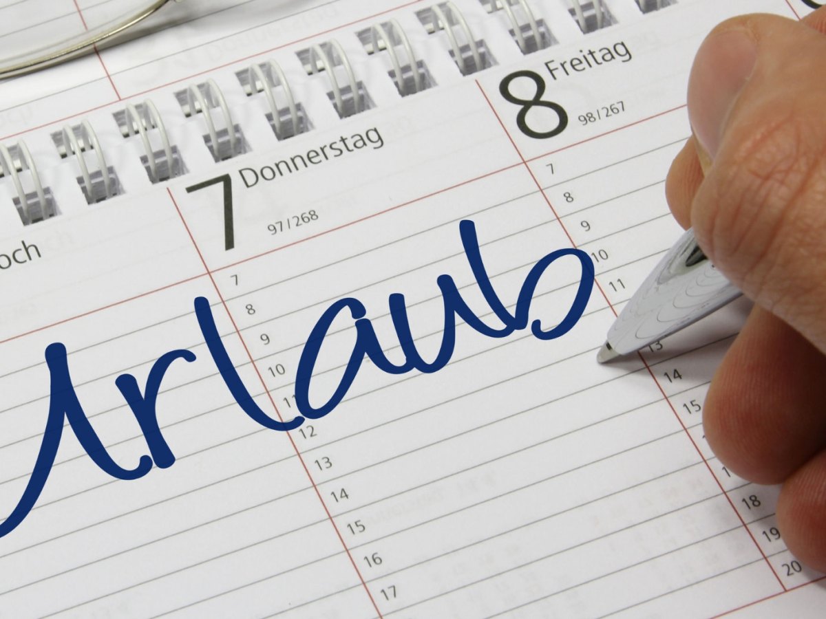 Person schreib „Urlaub“ in seinen Terminkalender