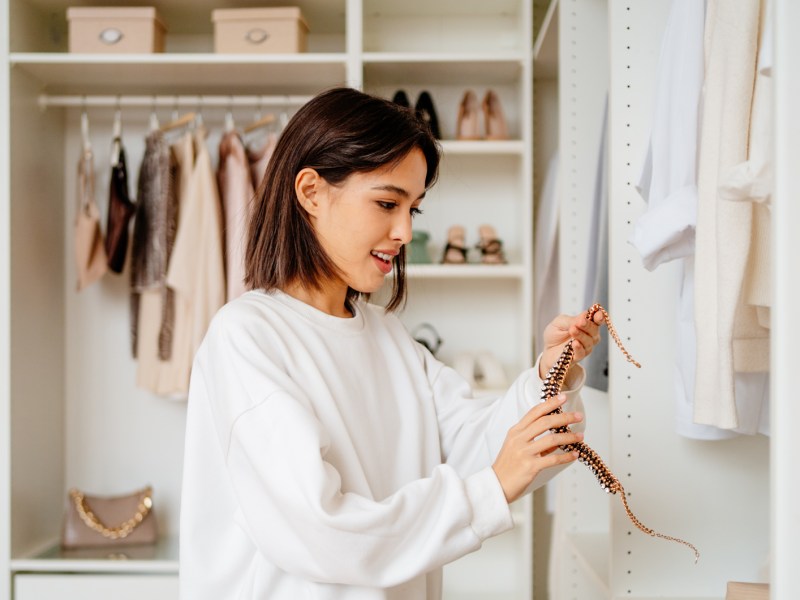 Frau, die ihren Kleiderschrank aussortiert und aufräumt.