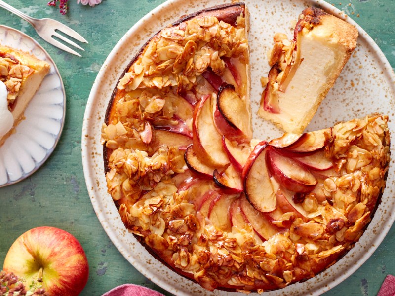 Apfelkuchen mit Bienenstich Topping auf einem herbstlich gedeckten Tisch.