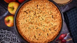 Apfelkuchen mit Streusel von oben, daneben liegen &Auml;pfel.