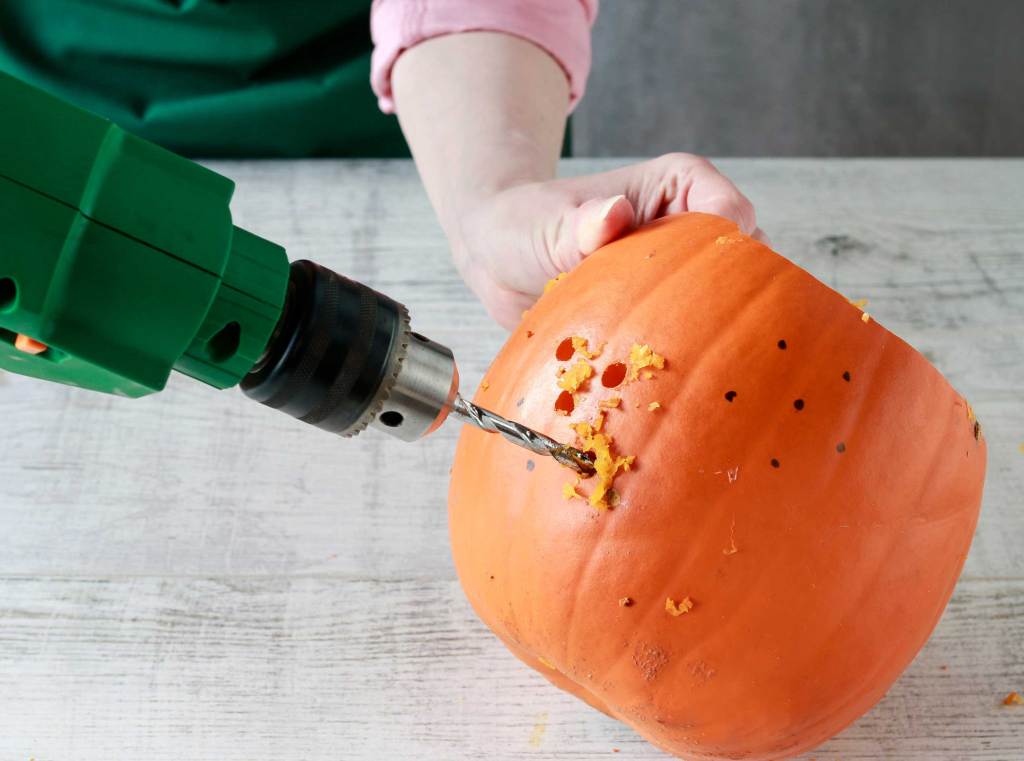 Frau zeigt, wie man einen Kürbis in eine Halloween-Laterne verwandelt