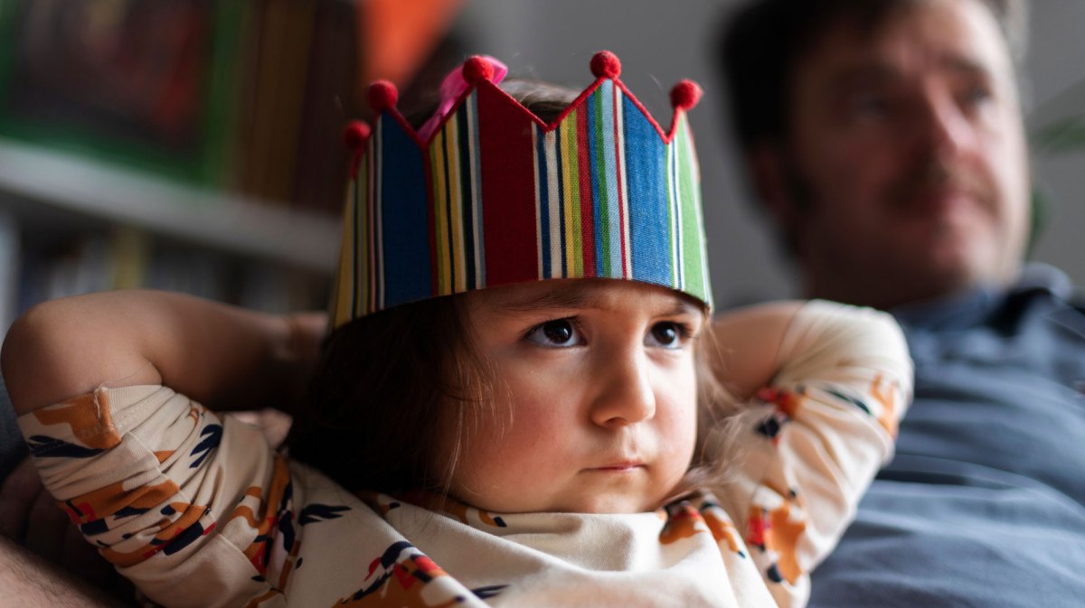 Porträt eines kleinen, wütenden Mädchens mit einer Geburtstagskrone auf dem Kopf.