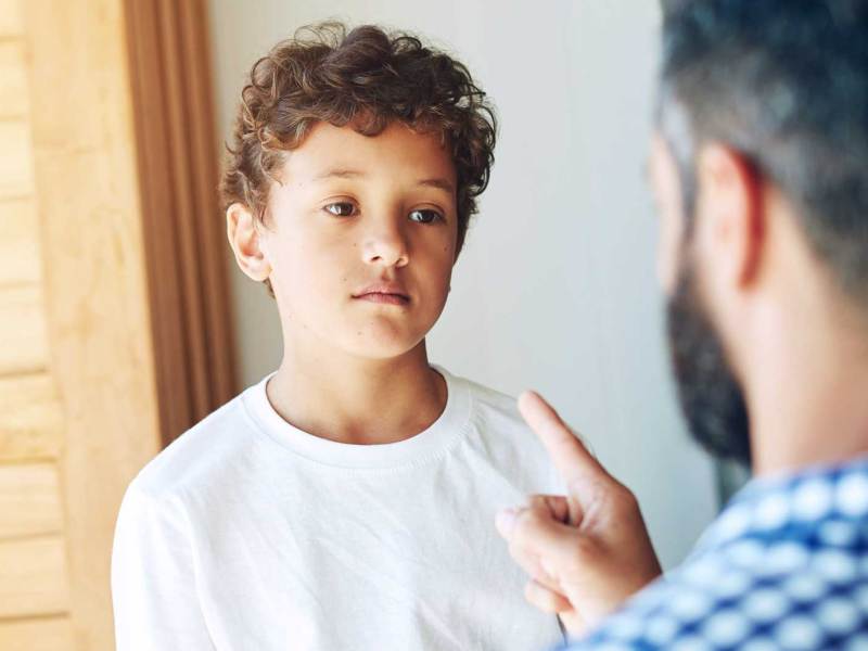 Vater schimpft mit seinem Sohn im Teenageralter. Der schaut genervt.