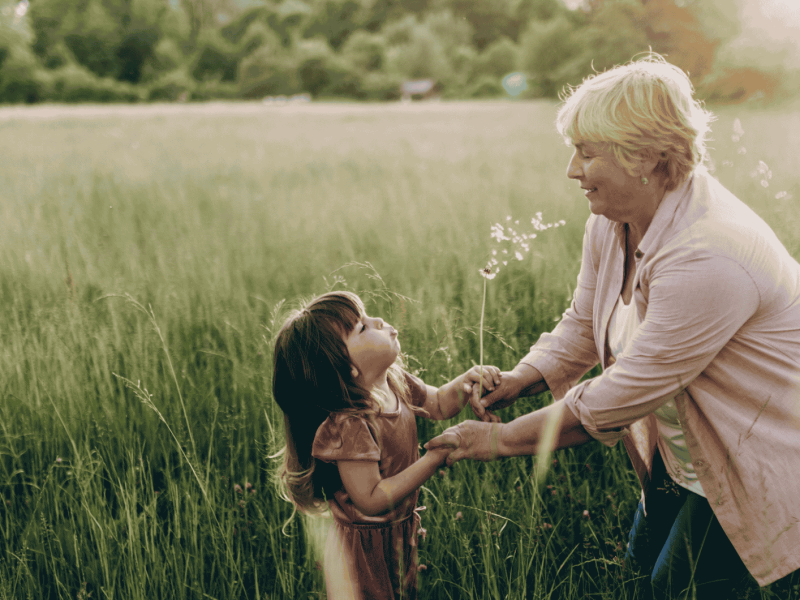 Gro&szlig;mutter und Enkelin auf einer Blumenwiese lachend