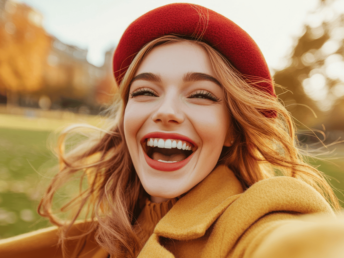 KI-generierte Frau im Herbst, die am Lachen ist, mit roter M&uuml;tze.