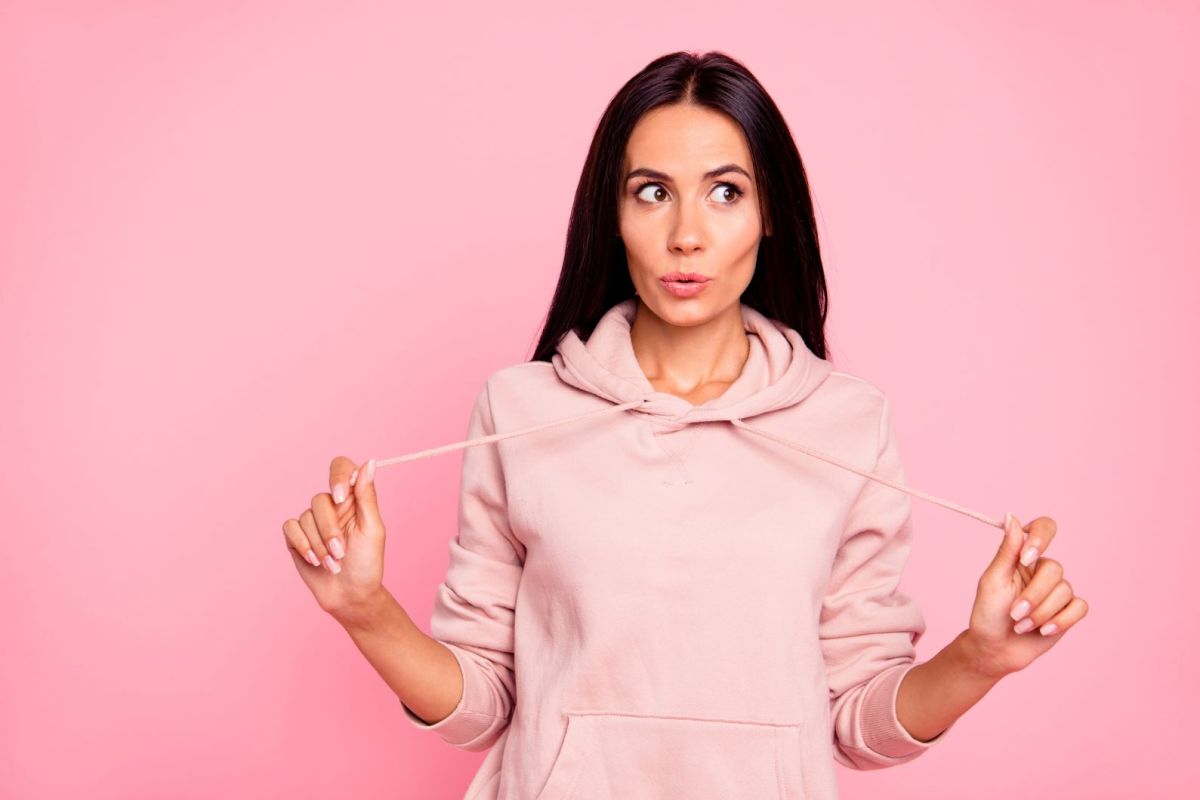 Frau mit braunen Haaren vor rosa Hintergrund mit rosa Hoodie an