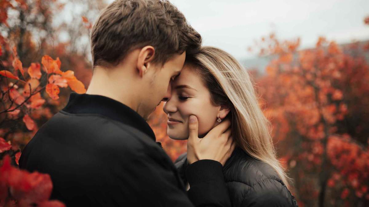 Verliebtes Paar an einem herbstlichen Tag steht draußen und umarmt sich liebevoll.