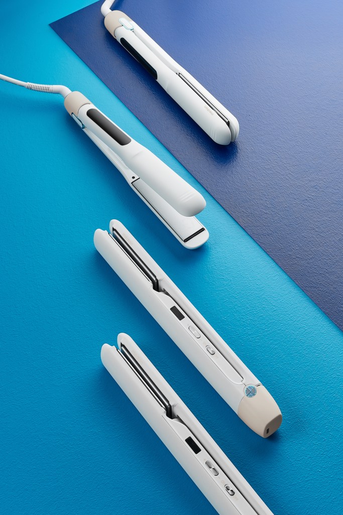 Vier moderne Haarglätter in Weiß auf einem zweifarbigen, blauen Hintergrund, sauber nebeneinander platziert.