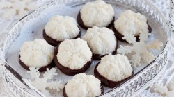 Kokosmakronen, die in Schokolade getunkt wurden, auf einem wei&szlig;en Teller.