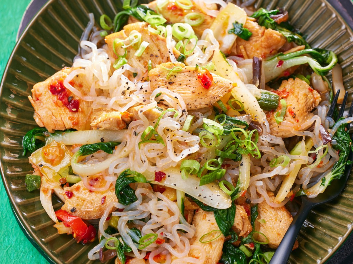 Low Carb Nudeln mit Asia-Gem&uuml;se und H&auml;hnchen in einer dunkelgr&uuml;nen Sch&uuml;ssel.