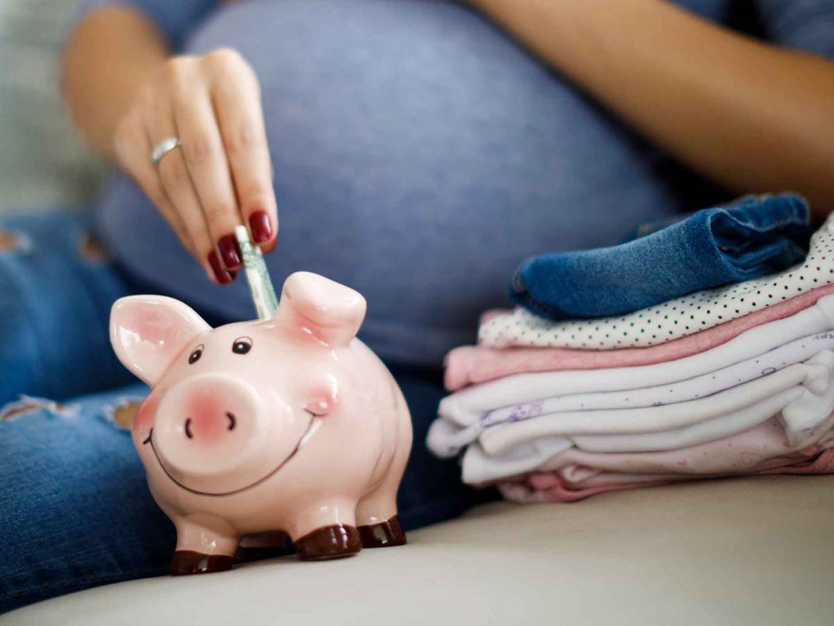 Schwangere Frau wirft Geldscheine in ein Sparschwein.