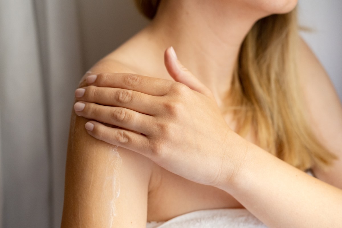 Frau cremt sich ihre Schulter im Badezimmer ein,