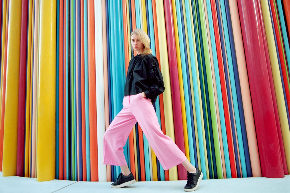 Frau läuft vor einer gestreiften, bunten Wand