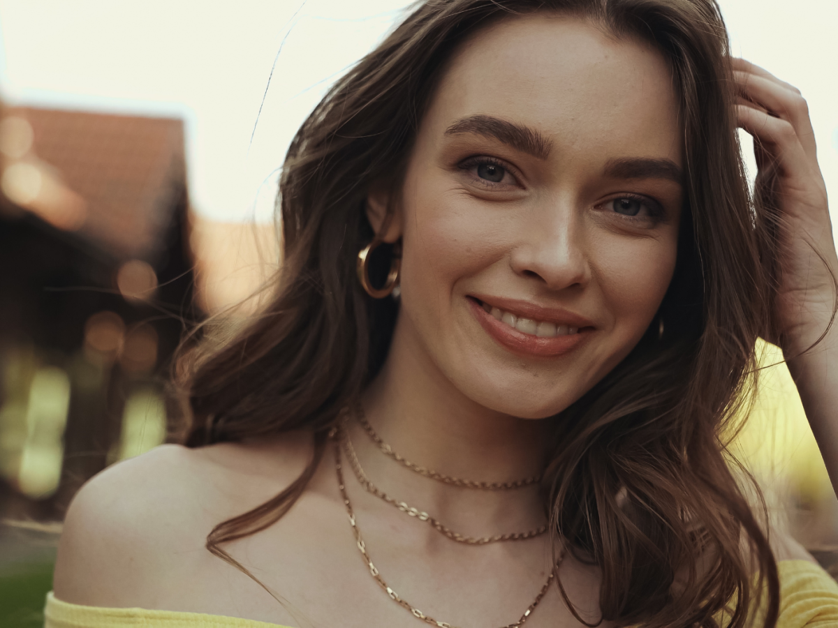 L&auml;chelnde Frau mit welligen, braunen Haaren.