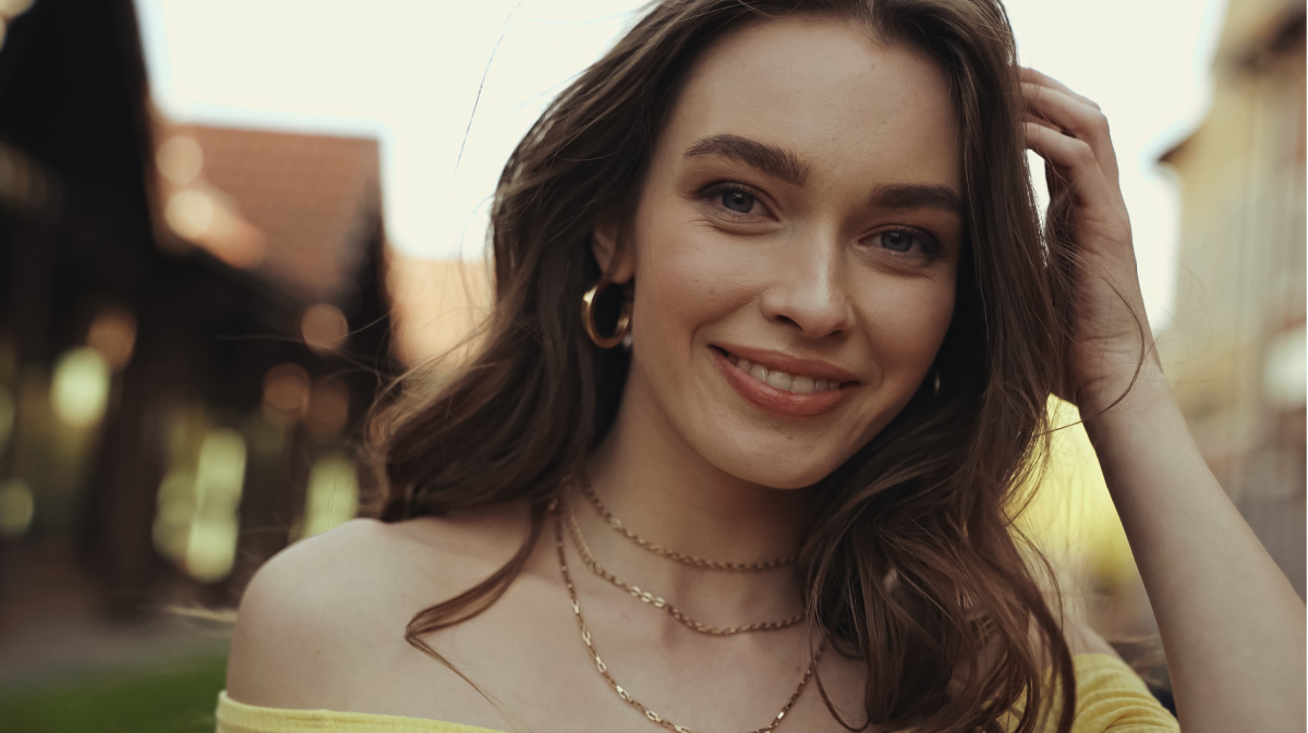 Lächelnde Frau mit welligen, braunen Haaren.