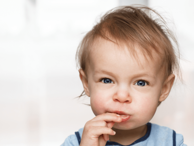 Kleinkind schaut in die Kamera und isst etwas