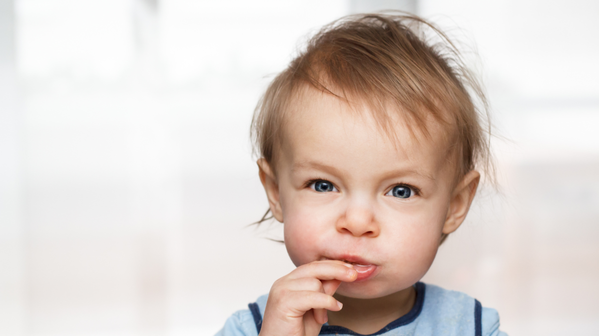 Kleinkind schaut in die Kamera und isst etwas