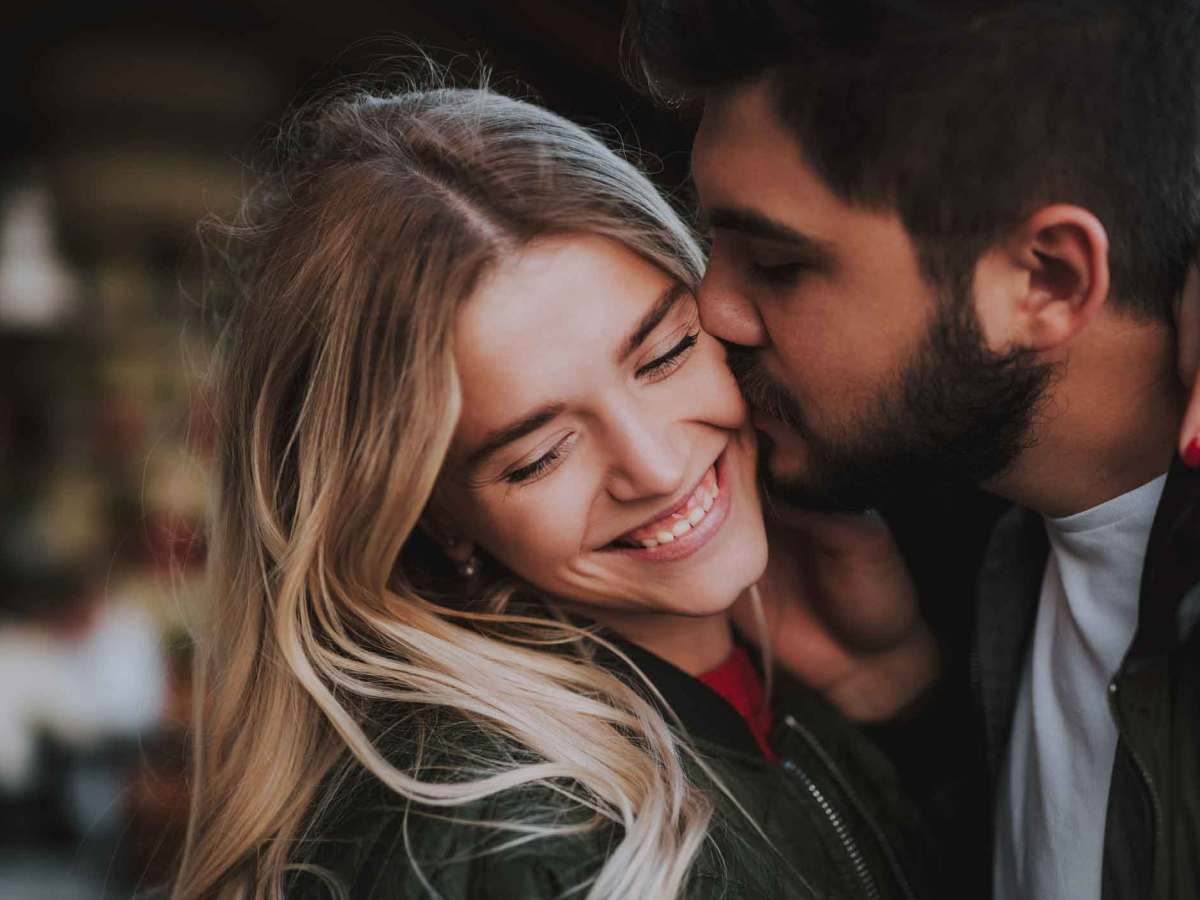 Mann k&uuml;sst Frau auf die Wange. Beide lachen und sind drau&szlig;en. Es ist Winter.