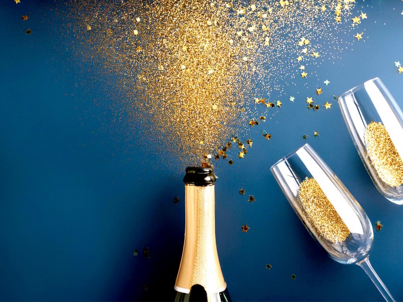 Flasche Sekt mit Glitzer und zwei Gläsern zum Anstoßen.