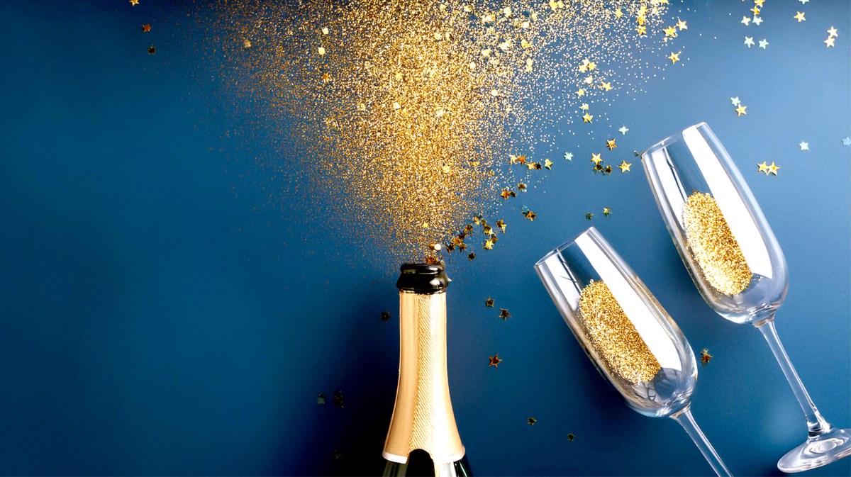 Flasche Sekt mit Glitzer und zwei Gläsern zum Anstoßen.