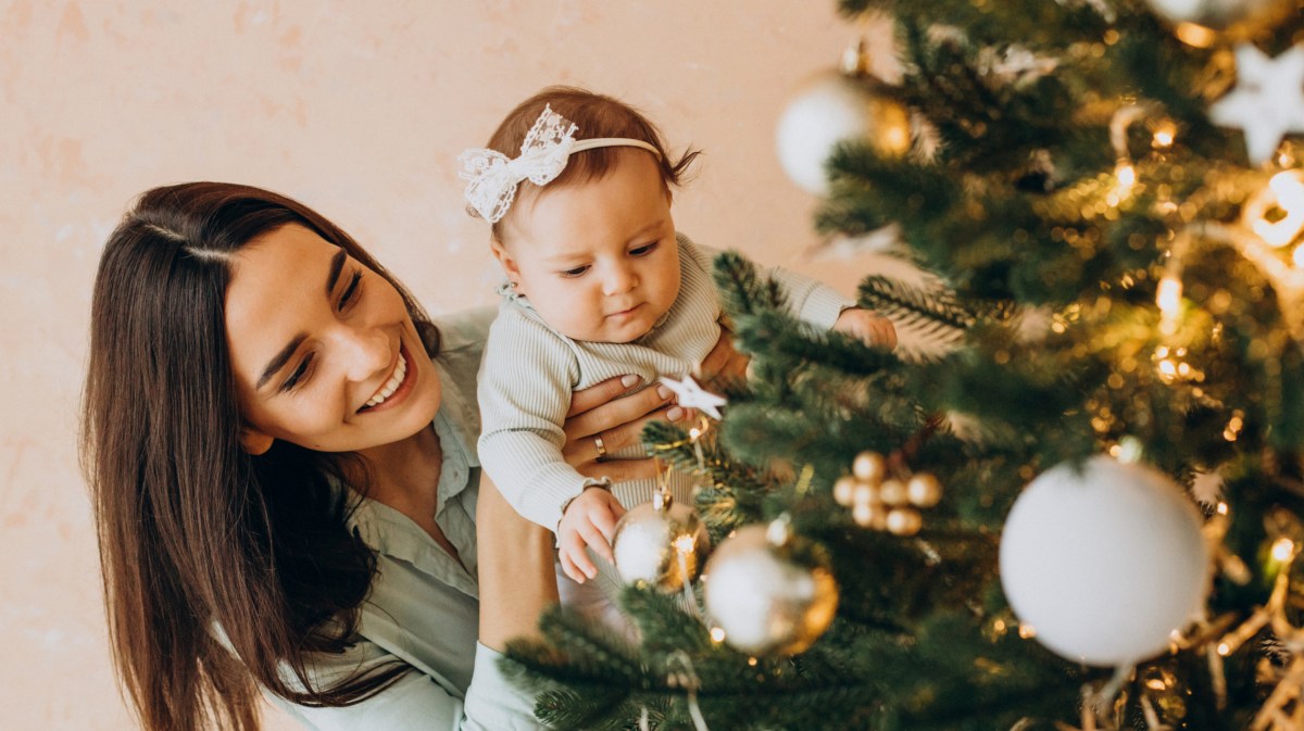 Mutter mit ihrem Baby schmückt den Weihnachtsbaum