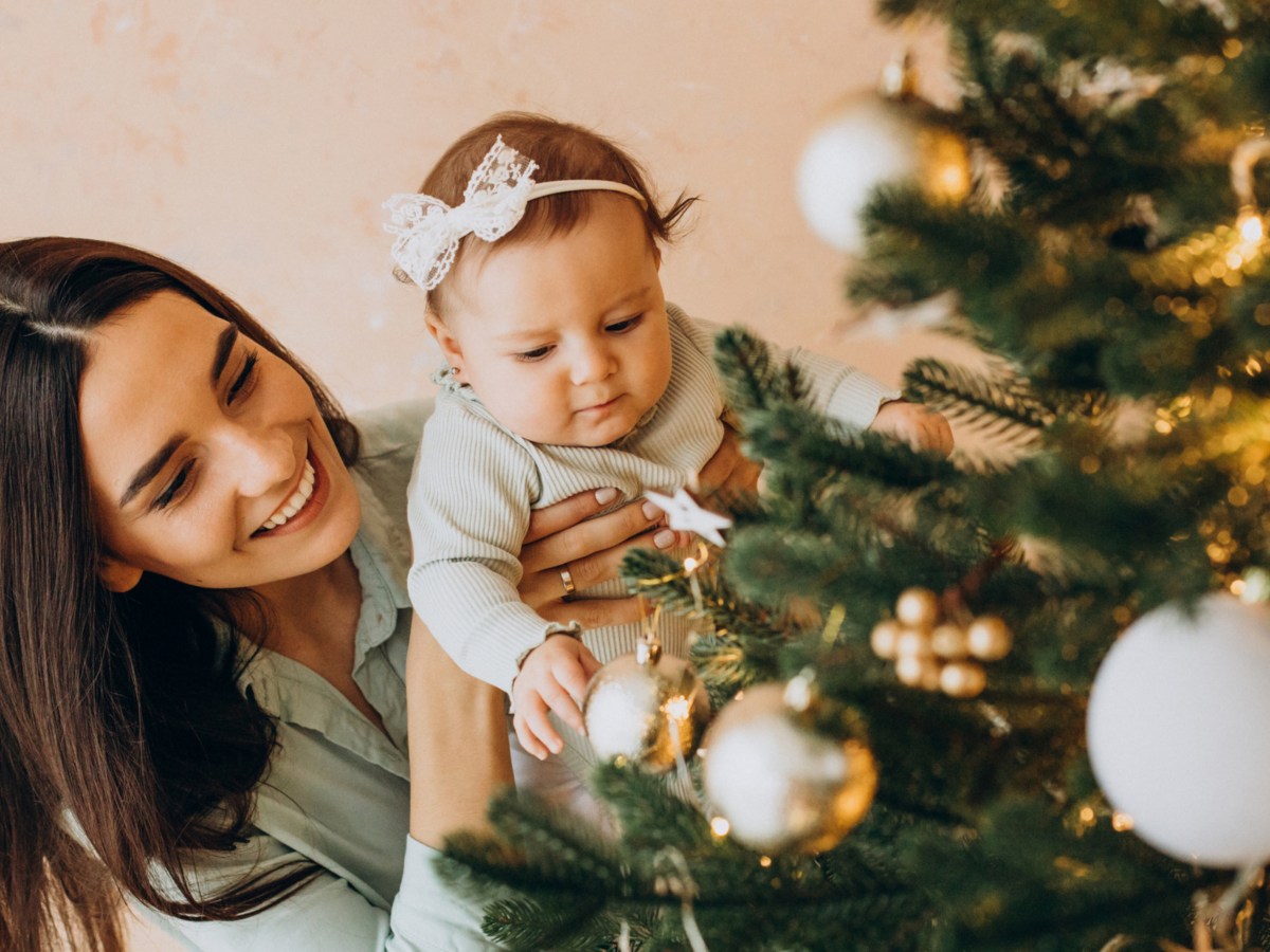 Mutter mit ihrem Baby schmückt den Weihnachtsbaum
