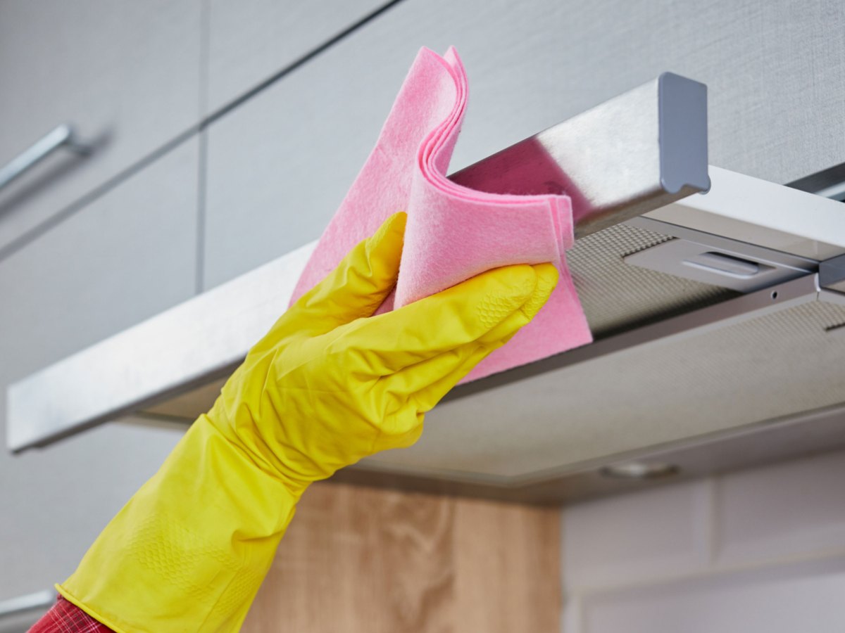 Person reinigt Dunstabzugshaube