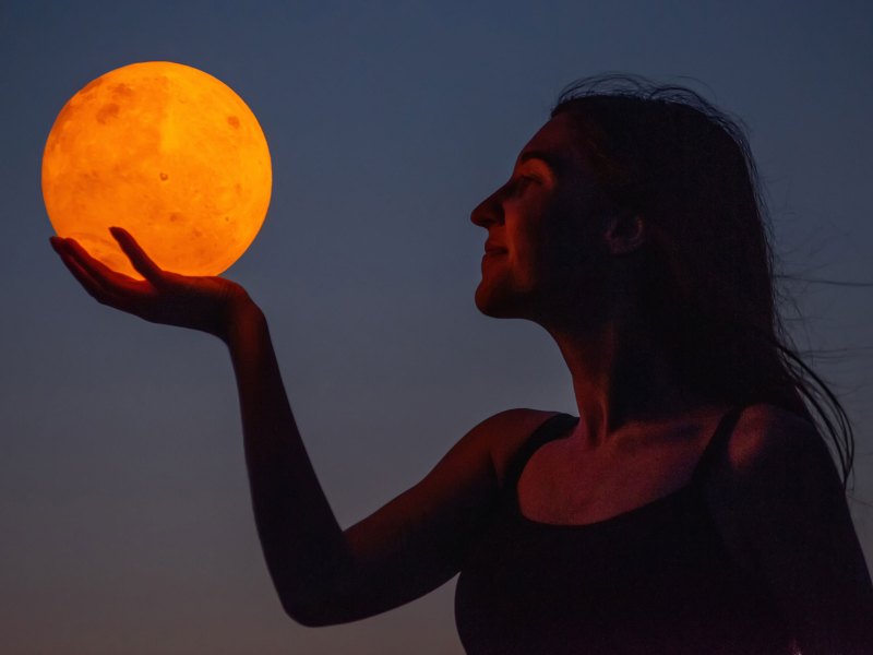 Frau hält Blutmond in der Hand bei Nacht