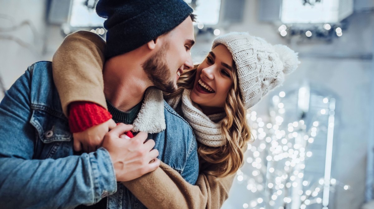 Mann und Frau in Winterbekleidung schauen sich lächelnd an