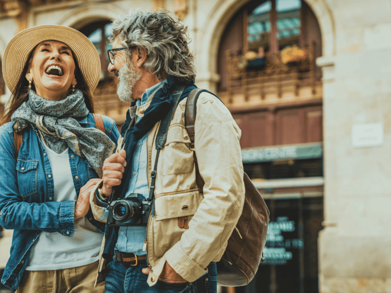 Älteres Pärchen lacht gemeinsam bei Städtetrip.