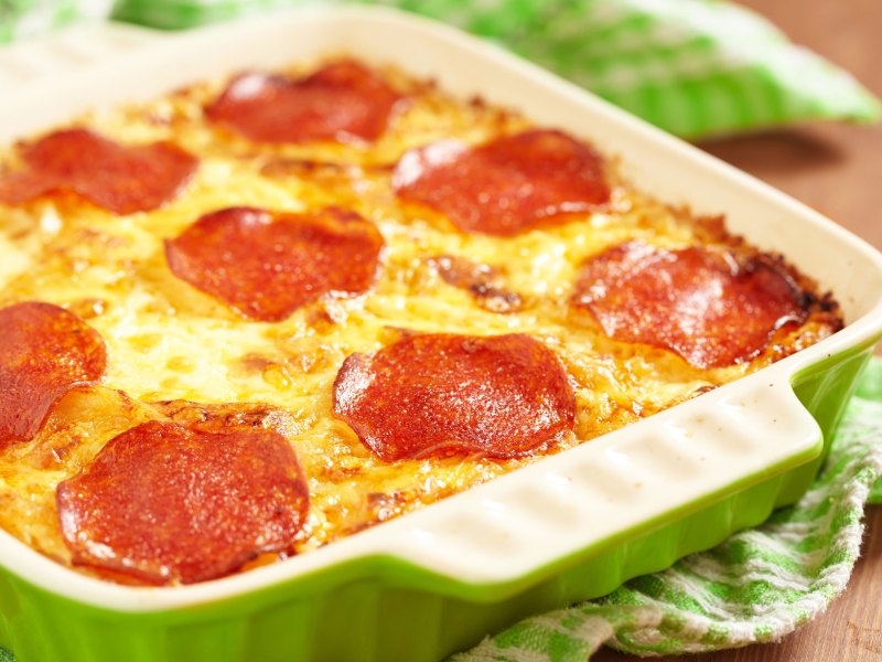 grüne Auflaufform mit Salami und Käse