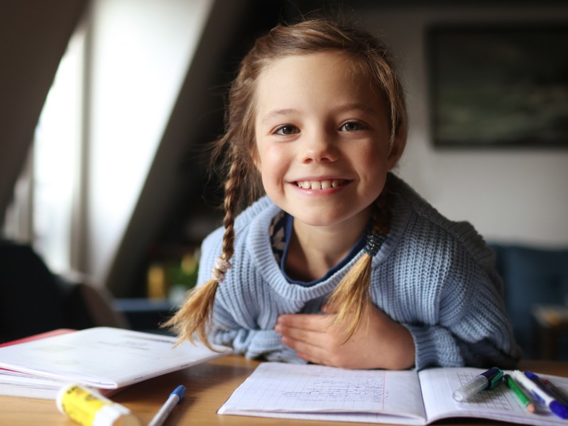 Porträt eines 8-jährigen Mädchens, das seine Hausaufgaben am Schreibtisch macht.
