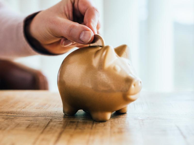 Frau wirft Geld in ein Sparschwein.