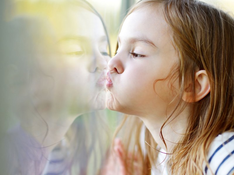Mädchen drückt Nase und Mund an das Fenster.