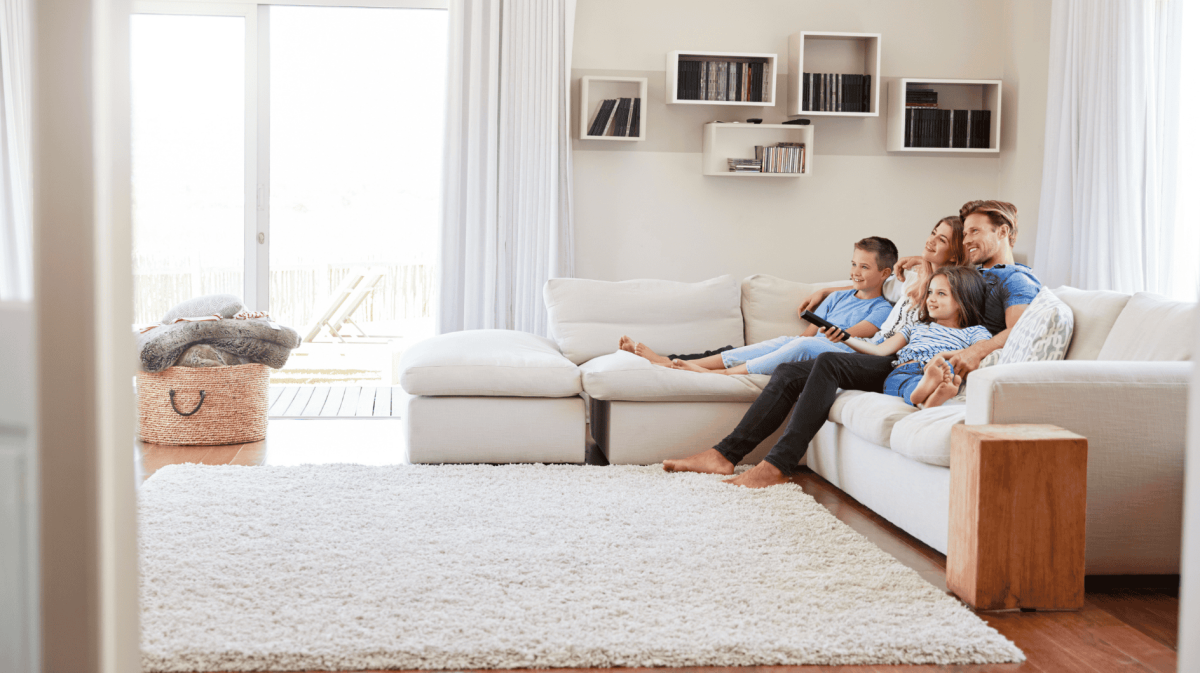 Familie sitzt im Wohnzimmer auf einer Couch