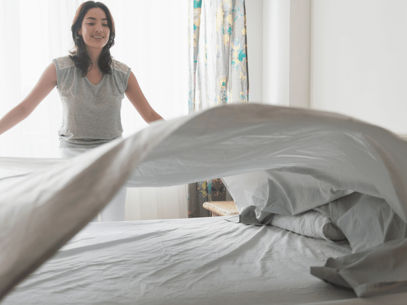 Frau schlägt Bettbezug auf einem Bett aus