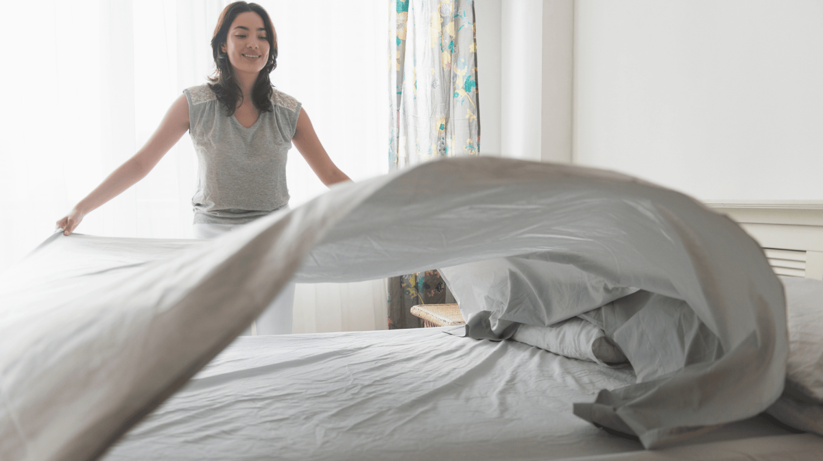 Frau schlägt Bettbezug auf einem Bett aus