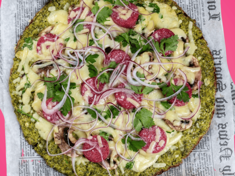 Brokkoli Pizza auf pinkem Untergrund.