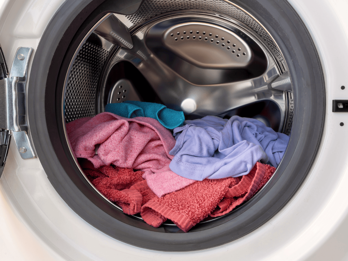 Offene Waschmaschine in der Handtücher und Putzlappen liegen.
