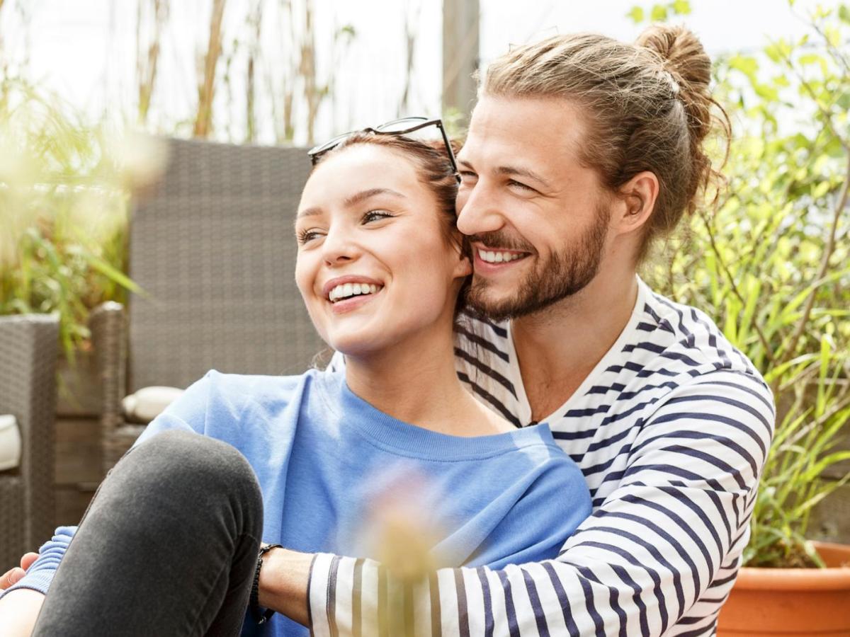Junges Paar sitzt draußen und kuschelt.